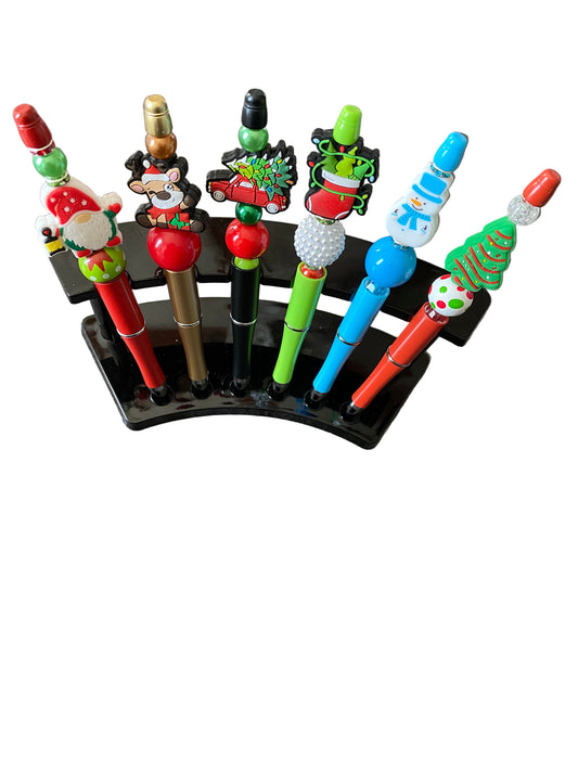 Colorful Christmas pens on a stand against a gray background